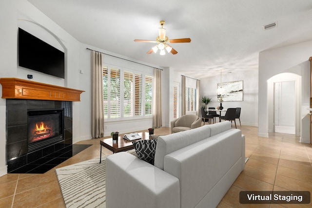 21510 Briar Landing Ln, Katy, TX 77450 - living room with light tile patterned floors, a tiled fireplace, ceiling fan, and arched walkways