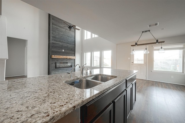 3022 Darlington Ct, Katy, TX 77494 - kitchen featuring a large fireplace, a ceiling fan, light stone countertops, wood finished floors, and decorative light fixtures