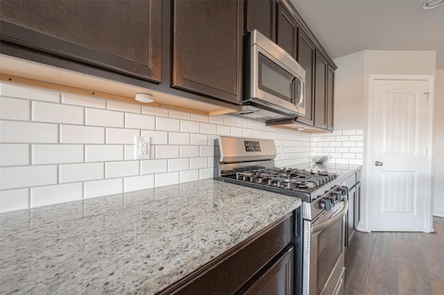 3022 Darlington Ct, Katy, TX 77494 - kitchen featuring appliances with stainless steel finishes, dark brown cabinets, dark wood finished floors, light stone countertops, and backsplash