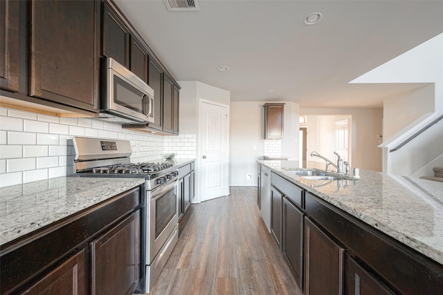 3022 Darlington Ct, Katy, TX 77494 - kitchen with stainless steel appliances, wood finished floors, light stone counters, decorative backsplash, and dark brown cabinetry