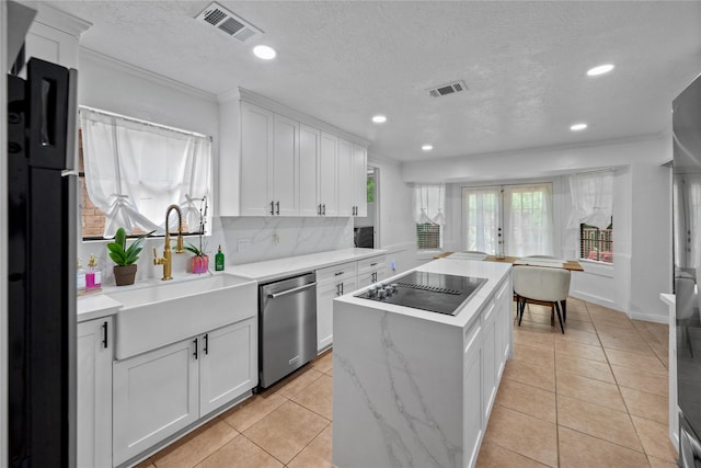 8519 Rebawood Dr, Humble, TX 77346 - kitchen featuring black appliances, a center island, white cabinetry, recessed lighting, and a textured ceiling