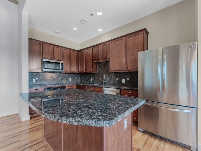 2700 Albany St Unit 3A, Houston, TX 77006 - kitchen with appliances with stainless steel finishes, light wood finished floors, dark stone counters, backsplash, and recessed lighting