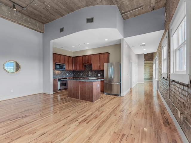 2700 Albany St Unit 3A, Houston, TX 77006 - kitchen with appliances with stainless steel finishes, open floor plan, light wood finished floors, a kitchen island, and a towering ceiling