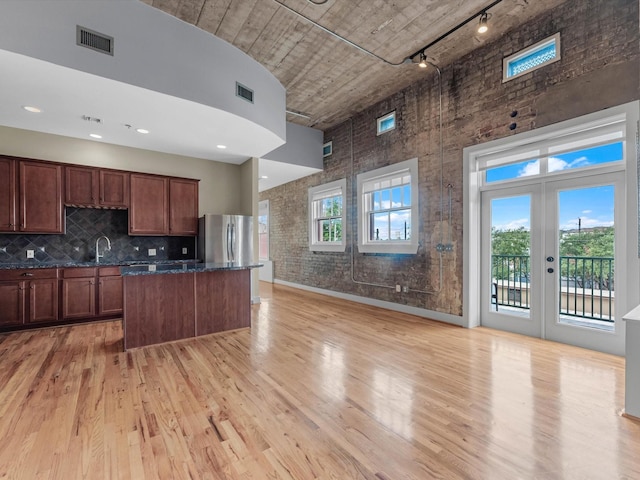 2700 Albany St Unit 3A, Houston, TX 77006 - kitchen featuring a high ceiling, freestanding refrigerator, rail lighting, a kitchen island, and light wood-style floors
