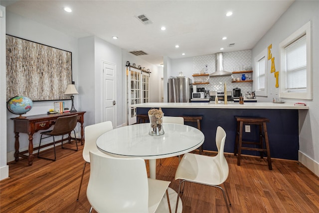 2212 Alabama St, Houston, TX 77004 - dining room with wood finished floors, a barn door, and recessed lighting