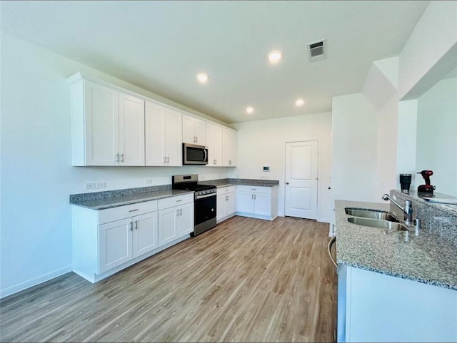 1009 Laguna Cove Dr, Katy, TX 77493 - kitchen with stainless steel appliances, light wood-type flooring, white cabinetry, stone countertops, and recessed lighting