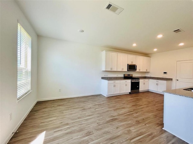 1009 Laguna Cove Dr, Katy, TX 77493 - kitchen featuring appliances with stainless steel finishes, healthy amount of natural light, light wood-type flooring, white cabinetry, and recessed lighting