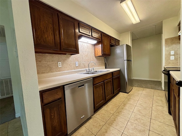 609 S Gray Ave, West Columbia, TX 77486 - kitchen featuring appliances with stainless steel finishes, light countertops, light tile patterned floors, dark brown cabinetry, and decorative backsplash