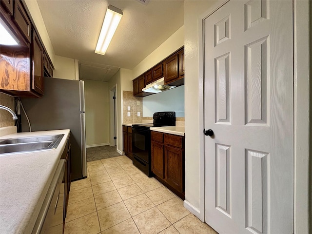 609 S Gray Ave, West Columbia, TX 77486 - kitchen with black electric range oven, light countertops, light tile patterned flooring, dark brown cabinetry, and under cabinet range hood