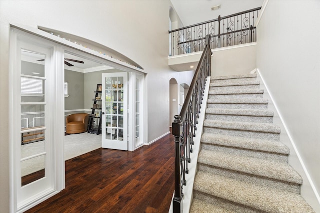 1402 Sullivan Springs Dr, Katy, TX 77494 - stairway featuring arched walkways, wood finished floors, a ceiling fan, ornamental molding, and a towering ceiling