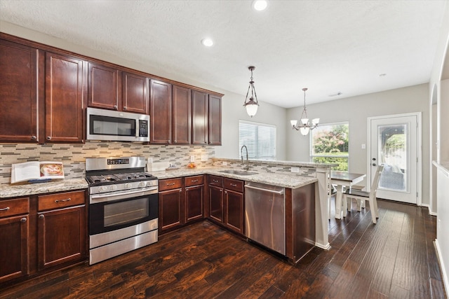 1402 Sullivan Springs Dr, Katy, TX 77494 - kitchen with stainless steel appliances, a peninsula, a chandelier, tasteful backsplash, and light stone counters