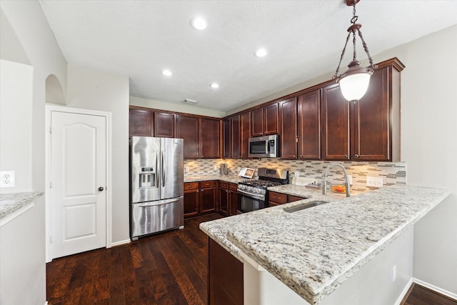 1402 Sullivan Springs Dr, Katy, TX 77494 - kitchen with appliances with stainless steel finishes, dark wood-style floors, a peninsula, tasteful backsplash, and hanging light fixtures