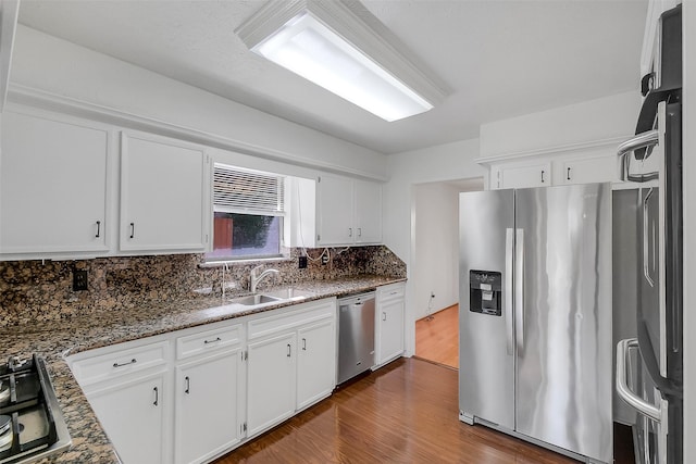 21307 Park Willow Dr, Katy, TX 77450 - kitchen featuring stainless steel appliances, wood finished floors, tasteful backsplash, white cabinets, and dark stone countertops
