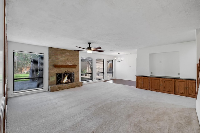 21307 Park Willow Dr, Katy, TX 77450 - unfurnished living room with a large fireplace, carpet, a chandelier, a textured ceiling, and a ceiling fan