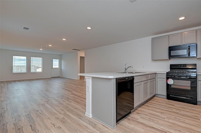 22156 Juniper Crossing Dr, New Caney, TX 77357 - kitchen featuring black appliances, gray cabinets, a peninsula, light wood-style flooring, and recessed lighting