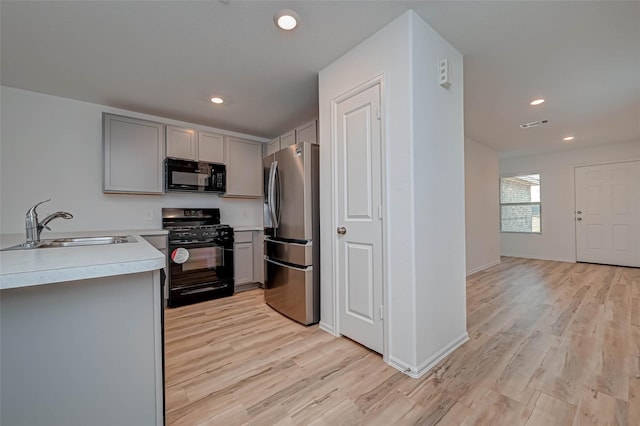 22156 Juniper Crossing Dr, New Caney, TX 77357 - kitchen with black appliances, gray cabinetry, light wood finished floors, light countertops, and recessed lighting