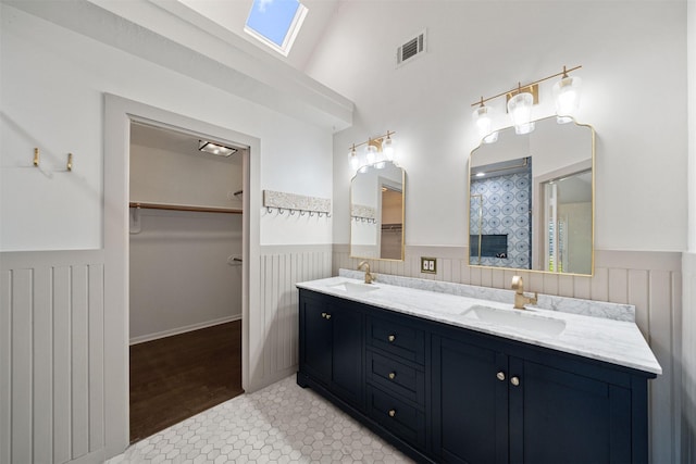 17706 Garnercrest Dr, Houston, TX 77095 - bathroom with wainscoting, double vanity, a spacious closet, and a skylight
