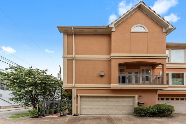 817 Rosine St, Houston, TX 77019 - rear view of property with an attached garage, stucco siding, concrete driveway, and a balcony