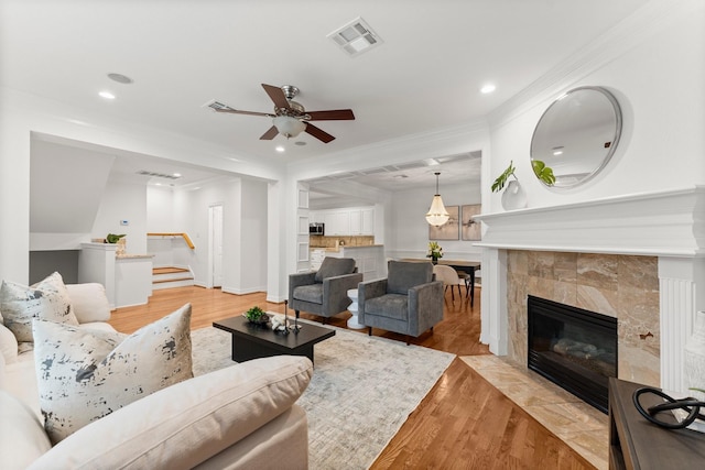 817 Rosine St, Houston, TX 77019 - living area with a tiled fireplace, ceiling fan, recessed lighting, light wood-style floors, and ornamental molding