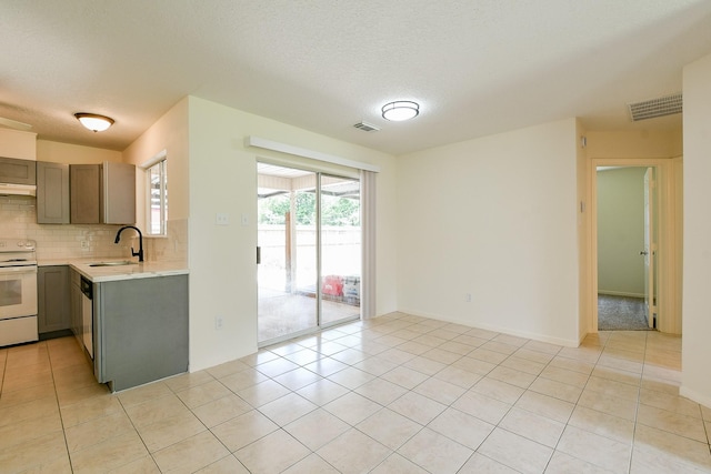 1117 Delores St, Kemah, TX 77565 - kitchen featuring white electric range, light countertops, light tile patterned floors, gray cabinetry, and backsplash