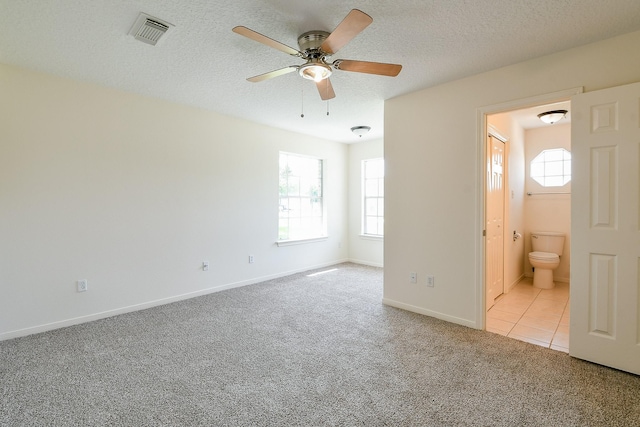 1117 Delores St, Kemah, TX 77565 - unfurnished bedroom featuring carpet floors, multiple windows, ensuite bath, a textured ceiling, and ceiling fan