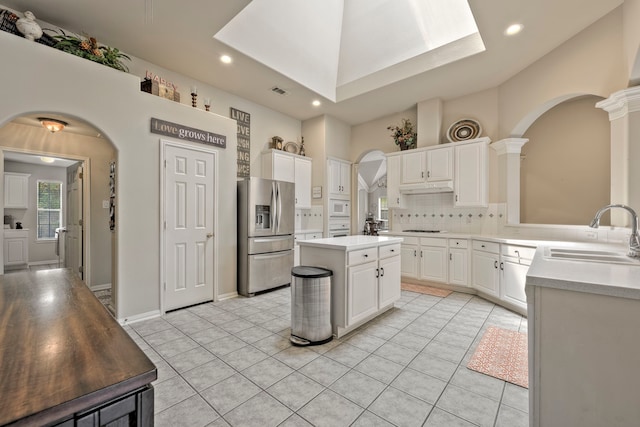 13615 Mierwood Manor Dr, Cypress, TX 77429 - kitchen featuring stainless steel fridge, arched walkways, under cabinet range hood, white microwave, and light countertops