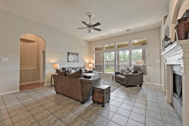 13615 Mierwood Manor Dr, Cypress, TX 77429 - living area featuring light tile patterned floors, ceiling fan, arched walkways, and a fireplace