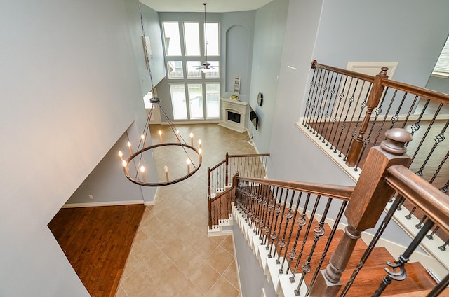 28722 Maple Red Dr, Katy, TX 77494 - stairs featuring a high ceiling, a chandelier, a ceiling fan, tile patterned flooring, and arched walkways