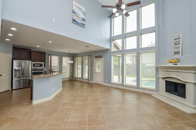 28722 Maple Red Dr, Katy, TX 77494 - kitchen featuring stainless steel appliances, open floor plan, a ceiling fan, light tile patterned floors, and a premium fireplace