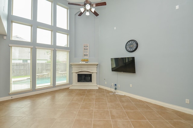 28722 Maple Red Dr, Katy, TX 77494 - unfurnished living room featuring light tile patterned flooring, a ceiling fan, a glass covered fireplace, and a high ceiling