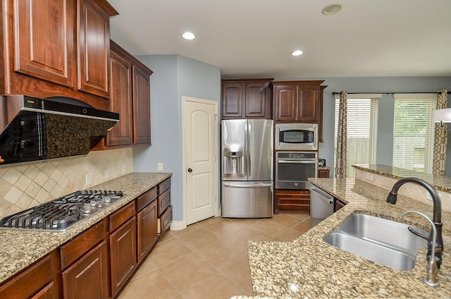 28722 Maple Red Dr, Katy, TX 77494 - kitchen with appliances with stainless steel finishes, decorative backsplash, light stone counters, light tile patterned floors, and range hood