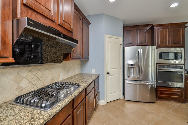 28722 Maple Red Dr, Katy, TX 77494 - kitchen with stainless steel appliances, tasteful backsplash, ventilation hood, light stone counters, and light tile patterned floors