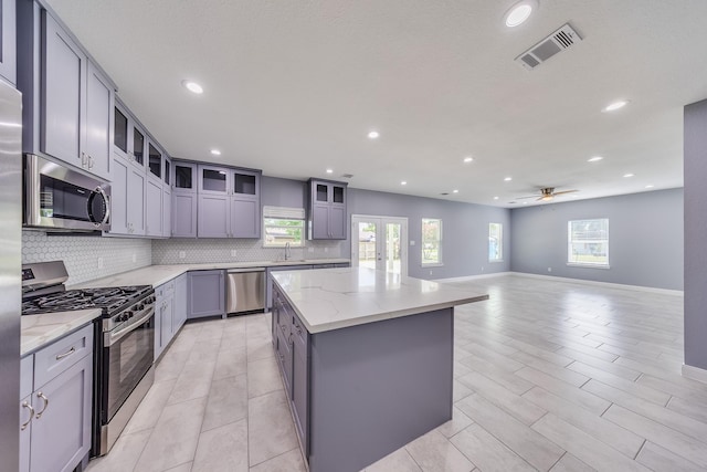 5402 Oriole St, Houston, TX 77017 - kitchen with stainless steel appliances, tasteful backsplash, a kitchen island, gray cabinets, and recessed lighting