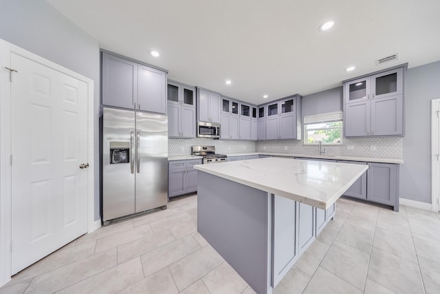 5402 Oriole St, Houston, TX 77017 - kitchen with stainless steel appliances, gray cabinetry, a center island, decorative backsplash, and recessed lighting