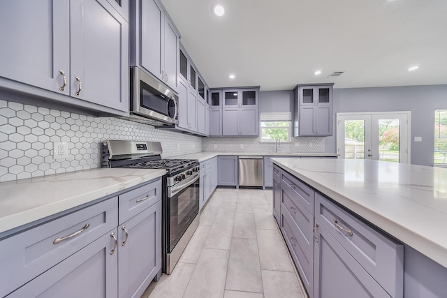 5402 Oriole St, Houston, TX 77017 - kitchen with stainless steel appliances, gray cabinets, backsplash, light stone counters, and recessed lighting