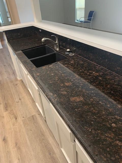 2425 Augusta Dr Unit 7, Houston, TX 77057 - kitchen view of light wood-type flooring, white cabinetry, and dark stone counters