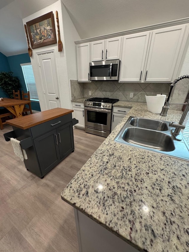 24223 Palomino Sage Trl, Katy, TX 77493 - kitchen featuring appliances with stainless steel finishes, white cabinets, tasteful backsplash, wood counters, and lofted ceiling