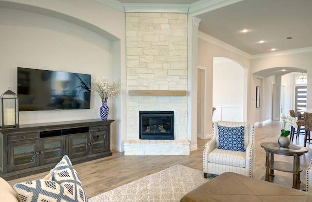 12607 Smokey Sunset Ct, Cypress, TX 77433 - living room featuring arched walkways, ornamental molding, wood finished floors, a stone fireplace, and recessed lighting