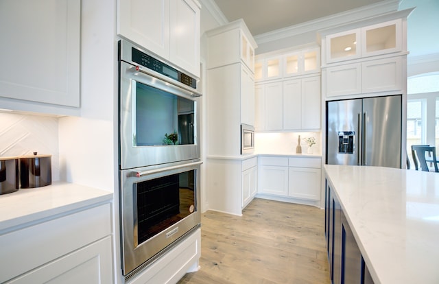 12607 Smokey Sunset Ct, Cypress, TX 77433 - kitchen with stainless steel appliances, ornamental molding, white cabinetry, light wood-style flooring, and glass insert cabinets