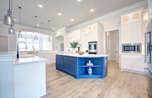12607 Smokey Sunset Ct, Cypress, TX 77433 - kitchen with stainless steel appliances, a large island, arched walkways, light wood-style floors, and ornamental molding