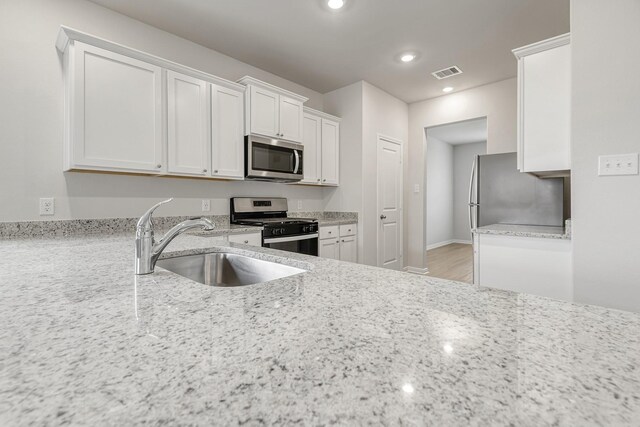 384 Tejas Trl, Waller, TX 77484 - kitchen with stainless steel appliances, white cabinets, recessed lighting, and light stone countertops