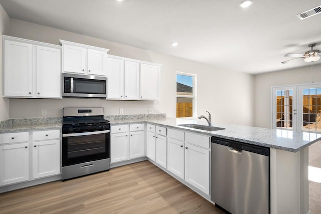 384 Tejas Trl, Waller, TX 77484 - kitchen with appliances with stainless steel finishes, a peninsula, white cabinets, healthy amount of natural light, and recessed lighting