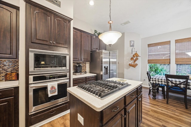 3732 Coral Reef Dr, Seabrook, TX 77586 - kitchen with stainless steel appliances, dark brown cabinets, tasteful backsplash, and light wood-style floors