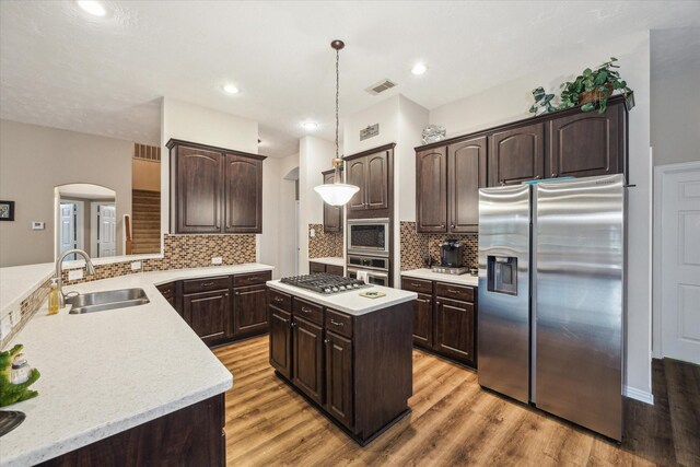 3732 Coral Reef Dr, Seabrook, TX 77586 - kitchen featuring stainless steel appliances, dark brown cabinetry, arched walkways, light countertops, and recessed lighting