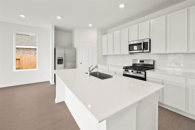 2435 Rooke Rd, Bryan, TX 77807 - kitchen featuring appliances with stainless steel finishes, dark wood-type flooring, white cabinets, recessed lighting, and an island with sink