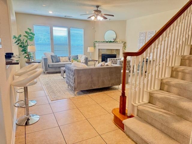 4126 Winesap Bend Dr, Stafford, TX 77477 - living area featuring ceiling fan, light tile patterned flooring, stairs, and a tiled fireplace