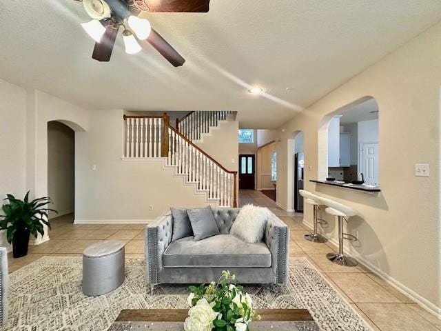 4126 Winesap Bend Dr, Stafford, TX 77477 - living area featuring arched walkways, light tile patterned flooring, a ceiling fan, and stairs