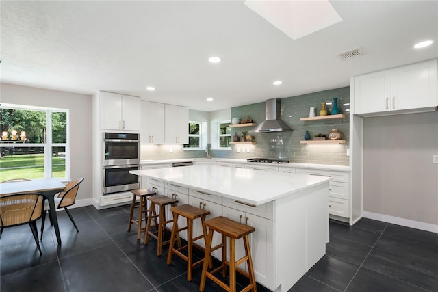 33933 Deer Creek Way, Stagecoach, TX 77355 - kitchen featuring wall chimney exhaust hood, stainless steel double oven, open shelves, gas stovetop, and backsplash