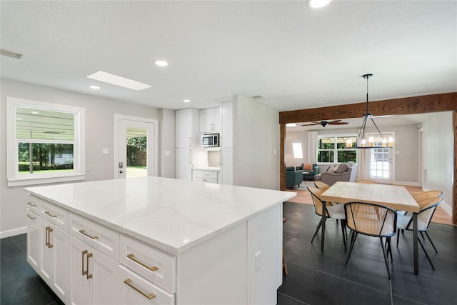 33933 Deer Creek Way, Stagecoach, TX 77355 - kitchen featuring stainless steel microwave, white cabinetry, recessed lighting, a center island, and hanging light fixtures