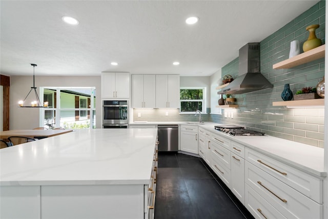 33933 Deer Creek Way, Stagecoach, TX 77355 - kitchen featuring open shelves, wall chimney range hood, stainless steel appliances, tasteful backsplash, and a chandelier